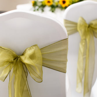 The Park Avenue Room set up for a wedding ceremony, white chairs with green ribbons