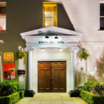 Front double doors and archway with columns at mercure gloucester bowden hall hotel floodlit at night
